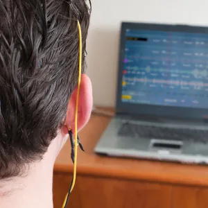  A person sitting in a chair with electrodes attached to their scalp, receiving neurofeedback treatment.