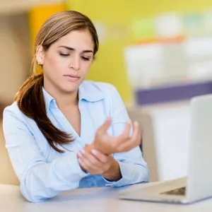 Woman holding wrist after typing on computer