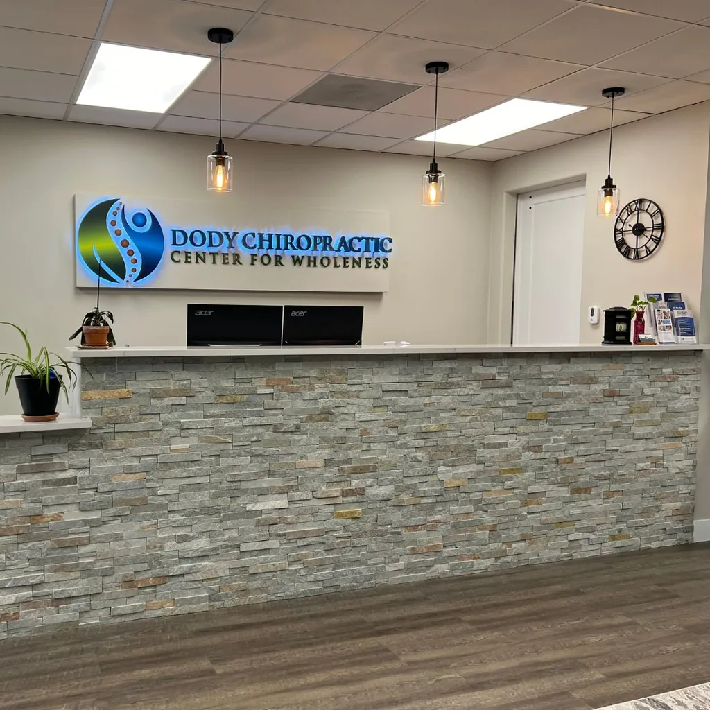 Reception desk with the backlit Dody Chiropractic Center for Wholeness sign in Littleton, Colorado